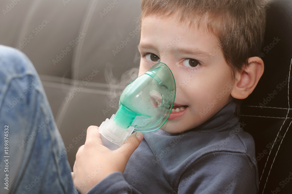 Little boy making inhalation with nebulizer at home