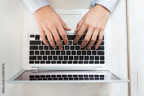 Woman hands typing on laptop computer close-up