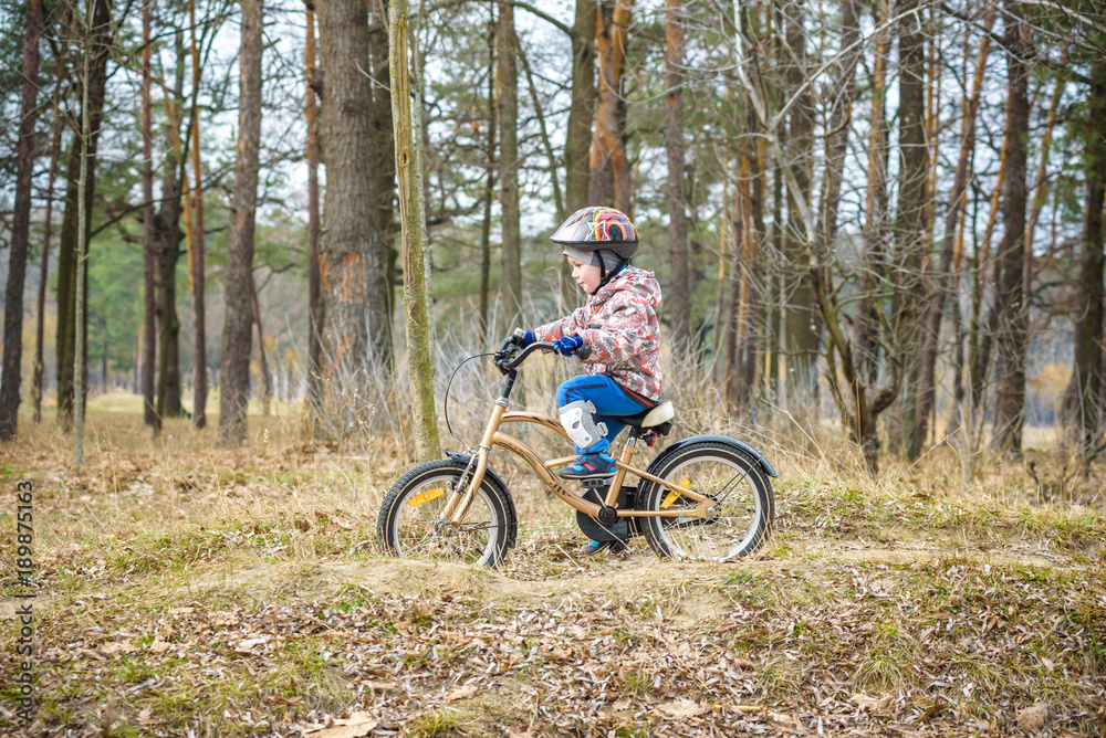 child on a bicycle in the forest in early morning. Boy cycling outdoors in helmet child on a bicycle in the forest in early morning. Boy cycling outdoors in helmet