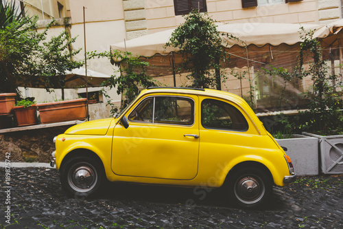 A yellow car in a small street in Rome photo