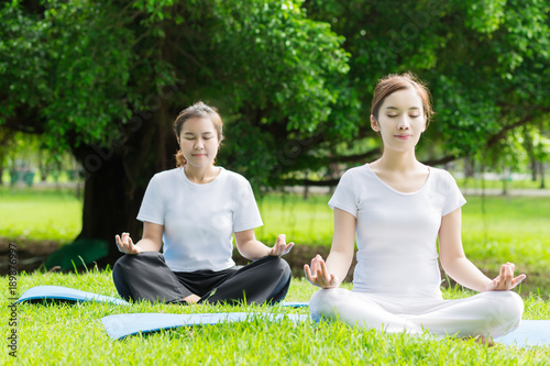 Two  Asian woman practicing yoga  at the Green park ,  Healthy lifestyle Concept.