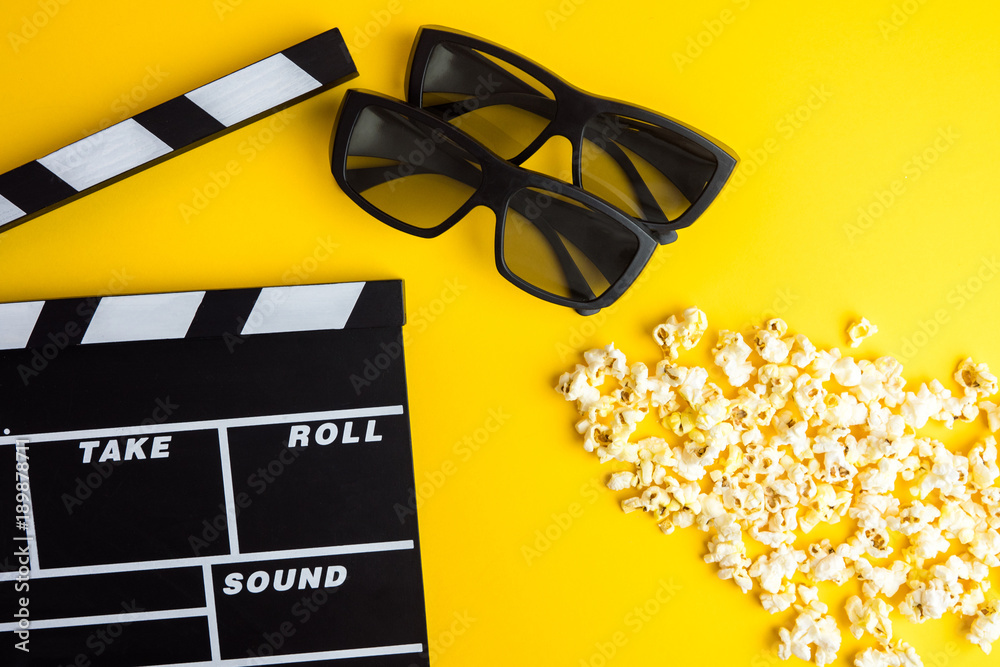 Cinema minimal concept. Watching film in the cinema. 3d glasses, popcorn, clapper board on yellow background 