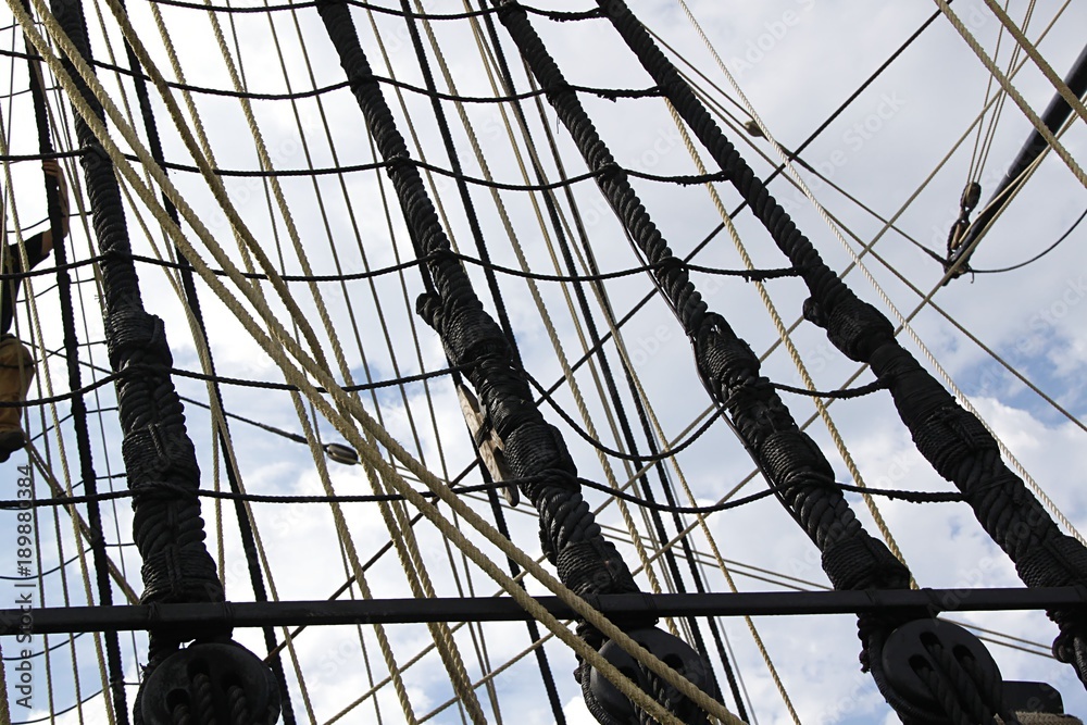 Detail of mast of ship. Detailed rigging with sails. Vintage sailing ship block and tackle. Detail of mast of ship. Detailed rigging with sails. Vintage sailing ship block and tackle.