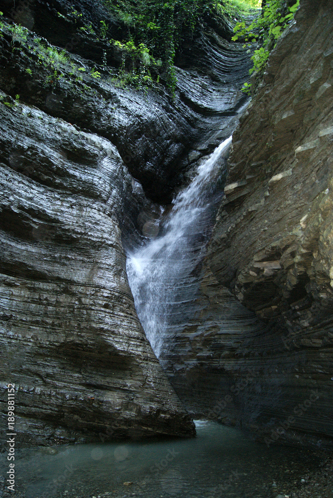 a fragment of a waterfall on a mountain stream in a narrow shady canyon..