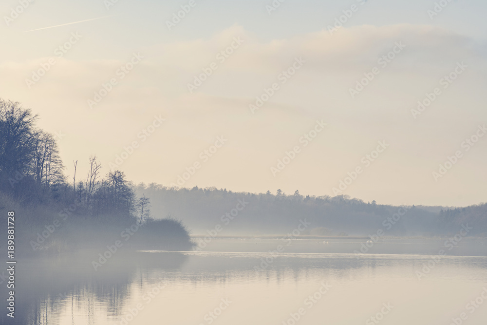 Lake scenery with morning fog and silent water