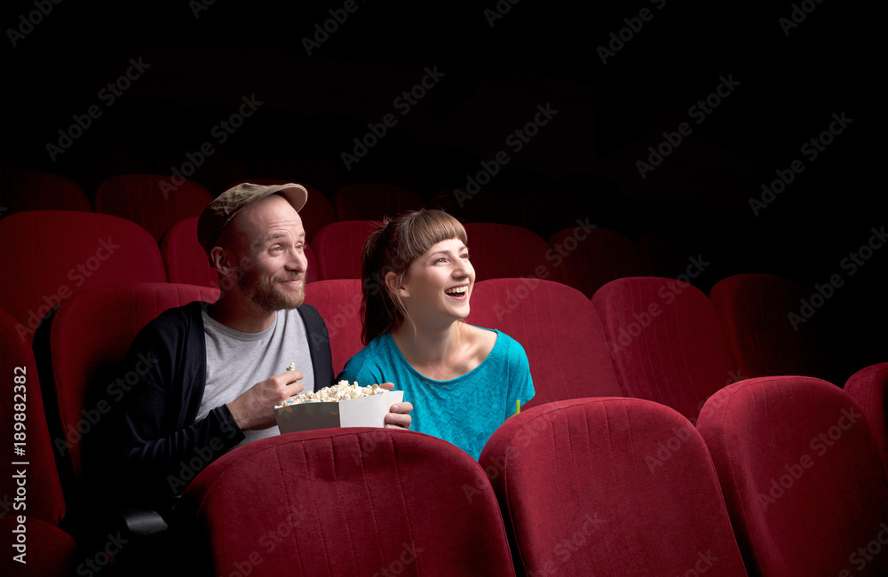 Fototapeta premium Young couple sitting at red movie theatre