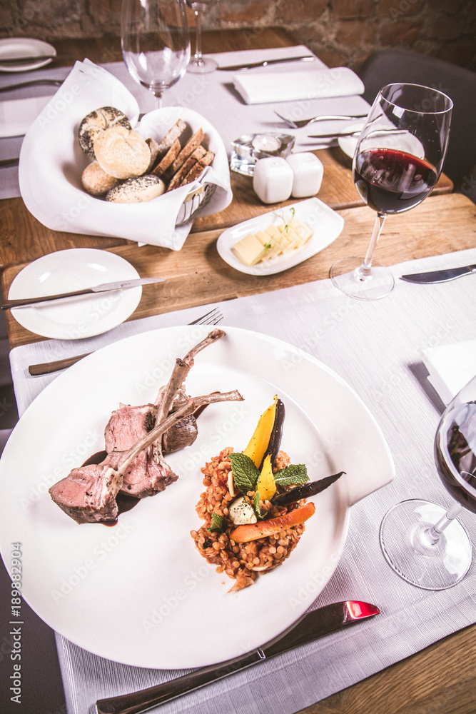 Lamb chops, braised lentils with mint, roast vegetables and rosemary sauce served in a restaurant
