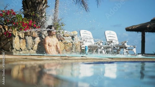 Man relaxing in swimming pool under pool waterfall, slow motion shot at 240fps photo