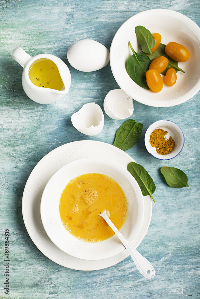 Ingredients for scrambled eggs with spinach and turmeric on the background. Top view. Copy space. Ingredients for scrambled eggs with spinach and turmeric on the background. Top view. Copy space.