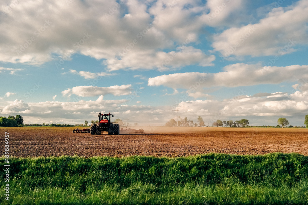 Fototapeta premium Farmer tilling land with tractor on farm in country