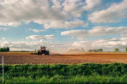 Farmer tilling land with tractor on farm in country