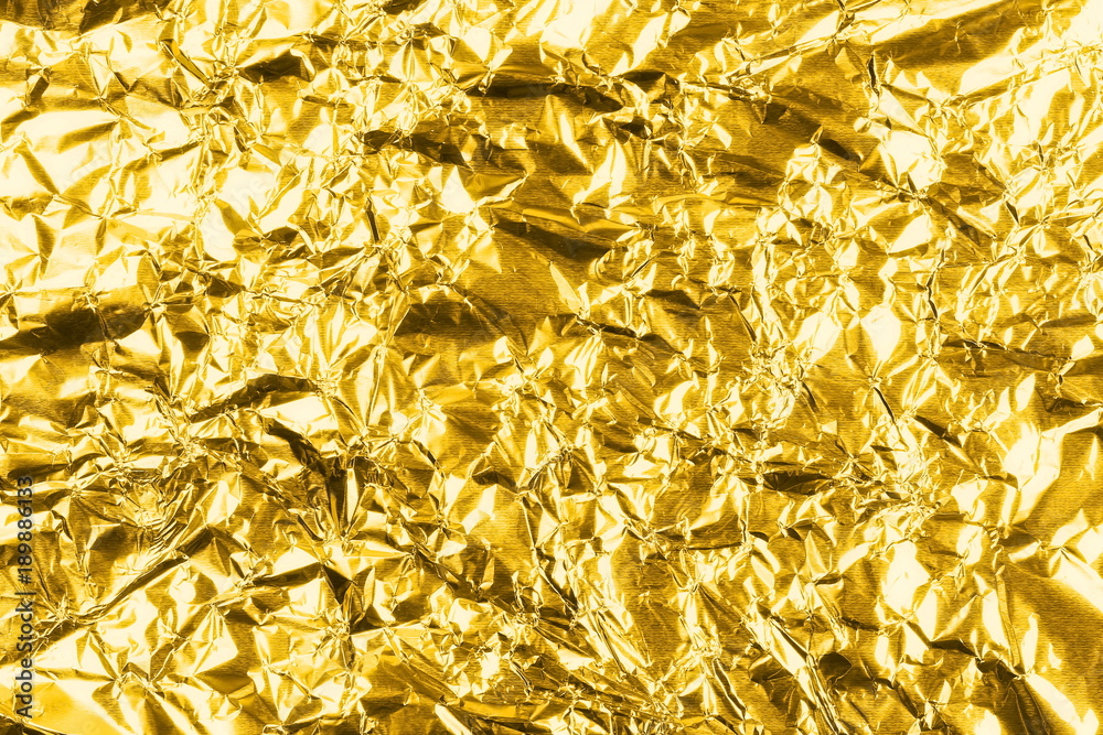 Crumpled golden aluminum foil background, abstract texture Stock