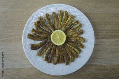 Anchovies rounded in a white plate with a lemon disk