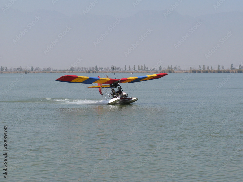 ultralight with pontoons and colorful wings landing on water ultralight with pontoons and colorful wings landing on water