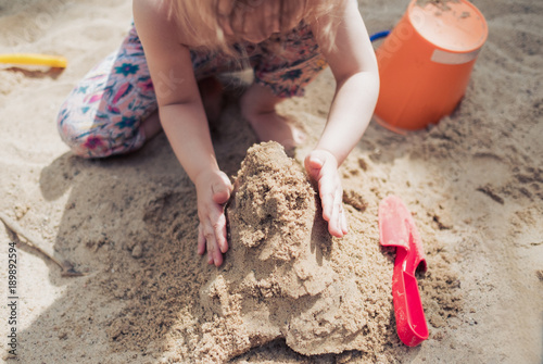 Kleines Mädchen spielt im Sand und baut eine Sandburg