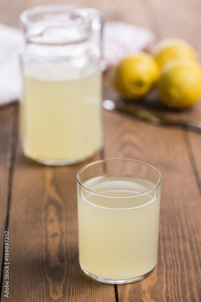 lemonade glass and carafe with lemons on wooden table