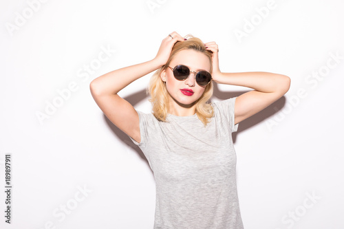 Stylish fashion sexy blonde bad crazy girl in a black t-shirt and rock sunglasses scream holding her head. Dangerous rocky emotional woman on White background
