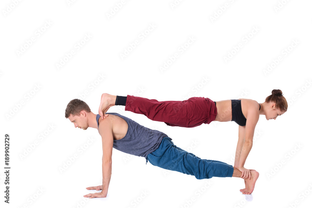 Obraz premium Young athletic couple practicing acroyoga. Balancing in pair