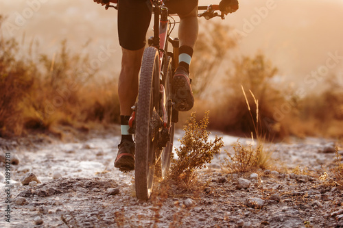 Male cyclist riding his full suspension mountain bike on dusty trail photo