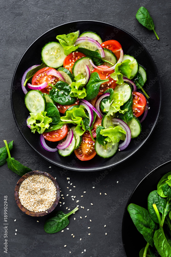 Healthy vegetable salad of fresh tomato, cucumber, onion, spinach, lettuce and sesame on plate. Diet menu. Top view. Healthy vegetable salad of fresh tomato, cucumber, onion, spinach, lettuce and sesame on plate. Diet menu. Top view.
