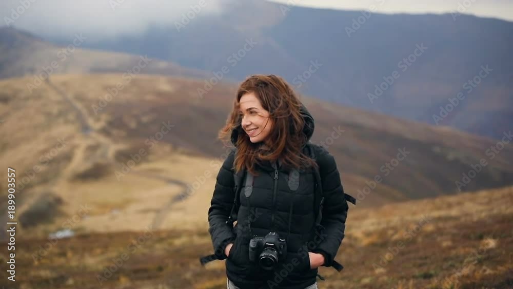 Young women photographer enjoying the views of the mountains. Wind develops hair. Slow motion. Young women photographer enjoying the views of the mountains. Wind develops hair. Slow motion.