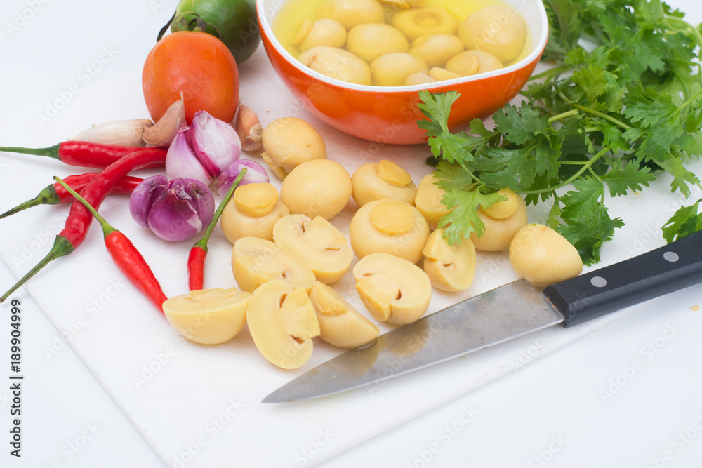 Cut whole champignon mushrooms in brine on white cutting board