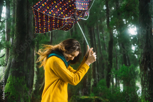 Woman with umbrella in windy forest