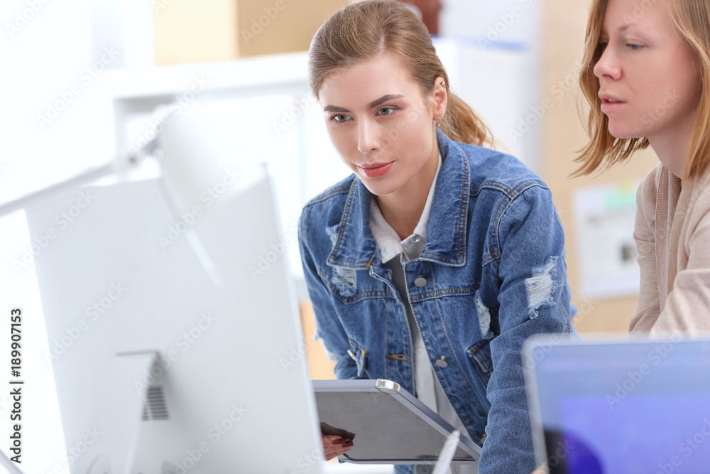 Two young woman standing near desk with instruments, plan and laptop. Two young woman standing near desk with instruments, plan and laptop.