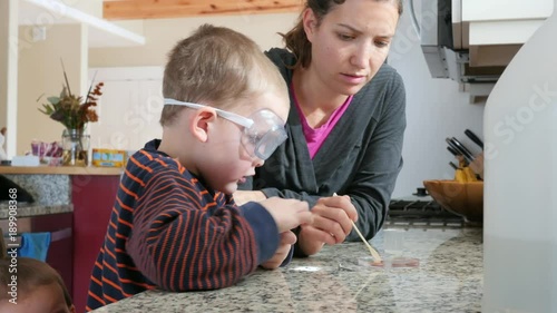 Dolly shot of kids doing science esperiment with their mom photo