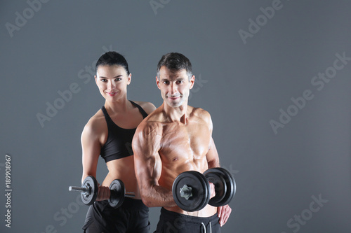 Athletic man and woman with a dumbells. Personal fitness instructor. Personal training.