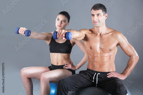 Two smiling people with fitness ball in the gym. Personal fitness instructor. Personal training. Gym workout.