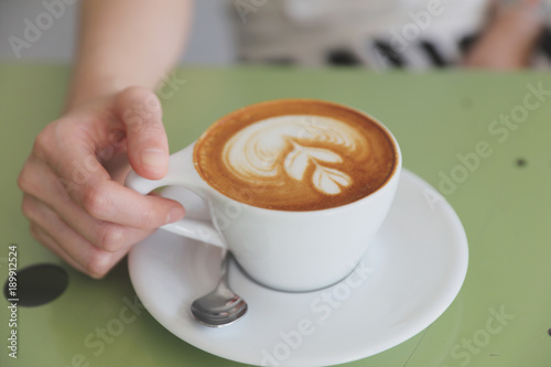 Cappuccino coffee with young woman hand