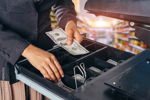 Female hand with money in supermarket shop. American dollar. us dollar. cash on cashier's desk. Hand giving cash. payday paying cashier access. photo