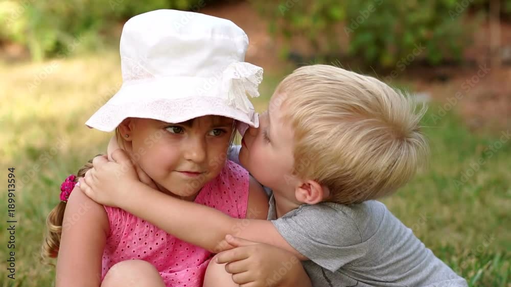 Cute little boy 4 years old kisses a little girl sitting in the park on ...