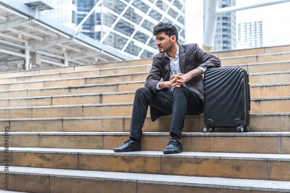Business man sitting on stair with luggage in the routine of working with determination and confidence. concept of business trip travel and transportation. Business man sitting on stair with luggage in the routine of working with determination and confidence. concept of business trip travel and transportation.