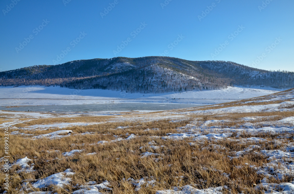 ice-covered Tugnuy river among wooded hills of southern Buryatia in early spring Sagan-Nur, Republic of Buryatia, Russia