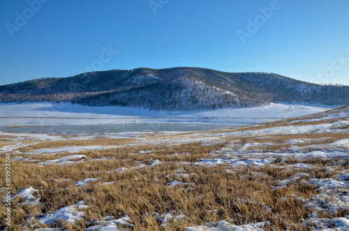 ice-covered Tugnuy river among wooded hills of southern Buryatia in early spring Sagan-Nur, Republic of Buryatia, Russia