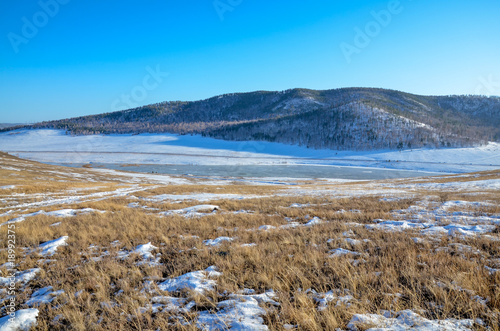 ice-covered Tugnuy river among wooded hills of southern Buryatia on a sunny day in early spring Sagan-Nur, Republic of Buryatia, Russia