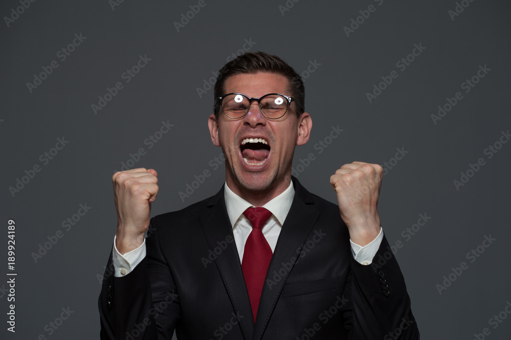 Portrait of an emotional happy businessman rejoicing at something and showing yes on gray background Portrait of an emotional happy businessman rejoicing at something and showing yes on gray background