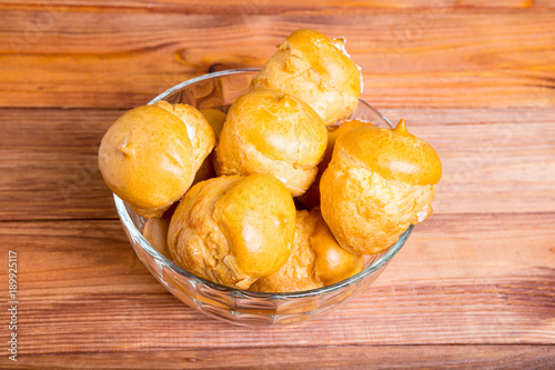 buns with cream in a glass vase on a timbered table photo