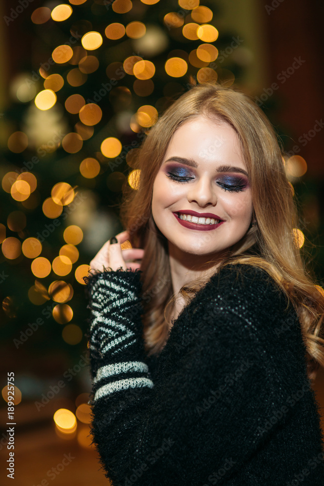 Smiling girl with beautiful makeup in front of christmas tree Smiling girl with beautiful makeup in front of christmas tree