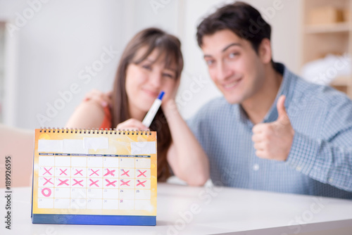 Young family in pregnancy planning concept with ovulation calend photo