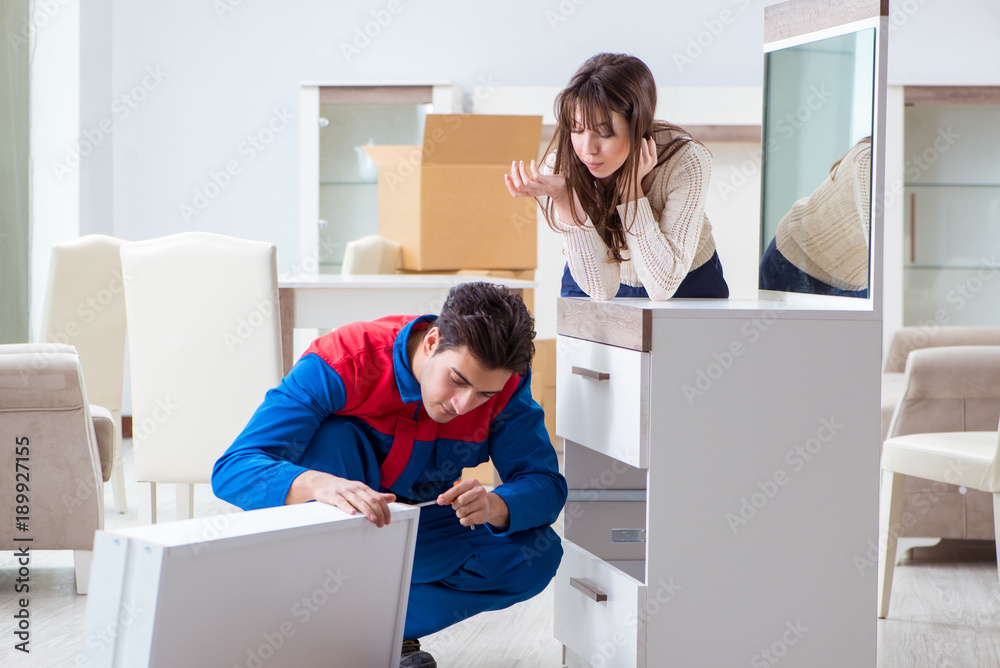 Contractor repairman assembling furniture under woman supervisio Contractor repairman assembling furniture under woman supervisio