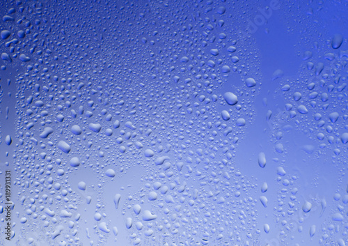 Glass blue texture with water drops on a blue background