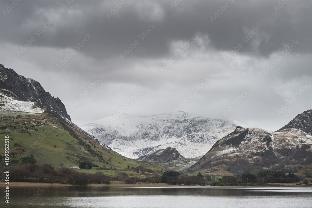 Beautiful Winter landscape image of Llyn Nantlle in Snowdonia National Park with snow capped mountains in background