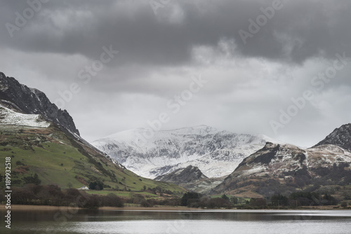 Beautiful Winter landscape image of Llyn Nantlle in Snowdonia National Park with snow capped mountains in background © veneratio