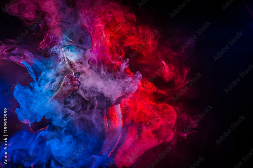 A man in a cloud of steam. Vaping man. A cloud of vapor. Vaping man holding a mod.
