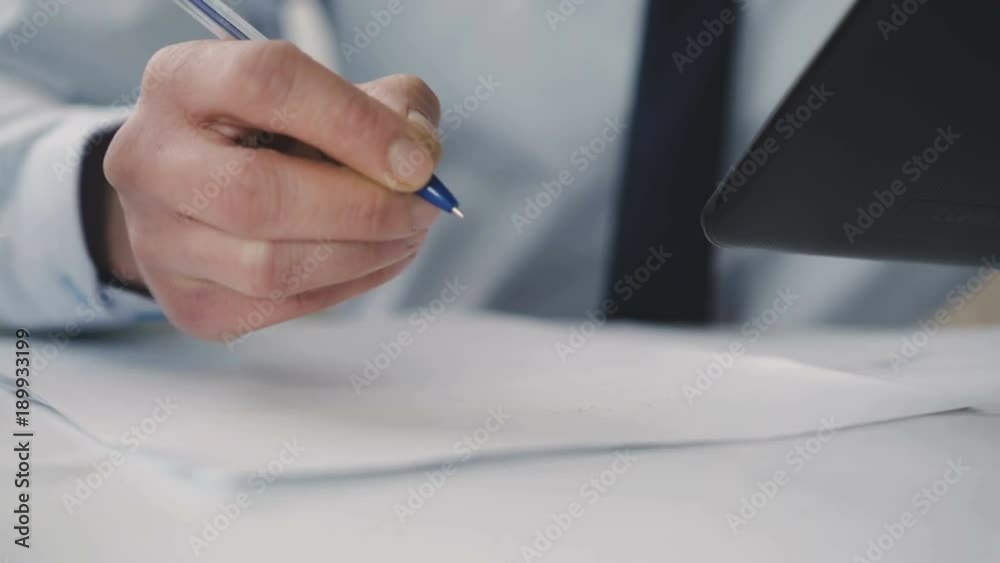 Tired thoughtful man writing on paper and using tablet in office. 4K Tired thoughtful man writing on paper and using tablet in office. 4K