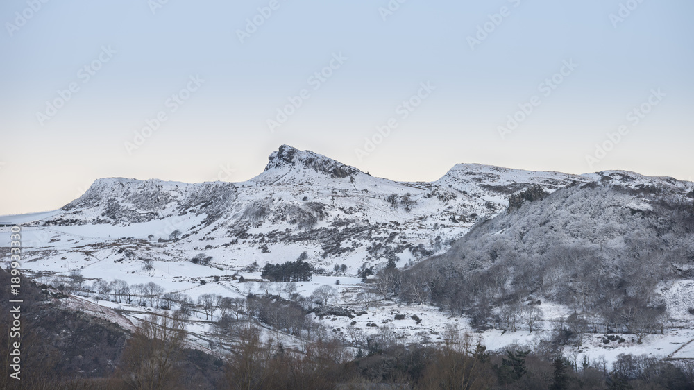 Fototapeta premium Beautiful Winter sunrise landscape image of Mount Snowdon and other peaks in Snowdonia National Park