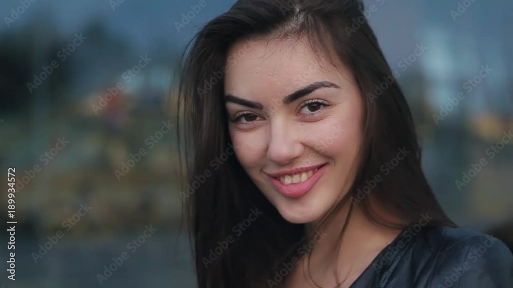 Beautiful girl smile in the evening. A brunette woman in a black leather jacket. Clouse up view. Beautiful girl smile in the evening. A brunette woman in a black leather jacket. Clouse up view.